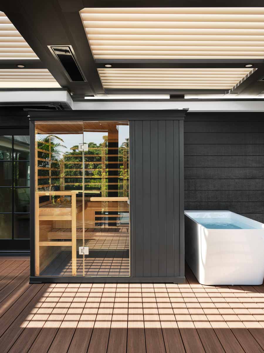 Matte black siding on his home and sauna creates striking contrast with the light colored pergola overhead