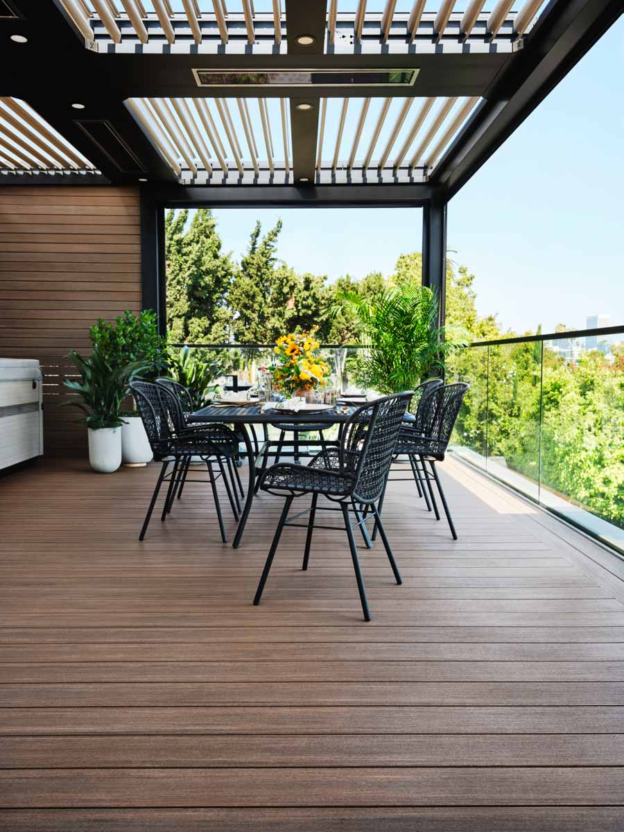 Table and chairs next to wrap around railing with a glass infill