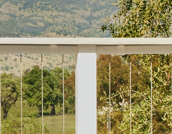 A close view of the white drink railing with tan top rail and cabling underneath looking out over Napa Valley. 