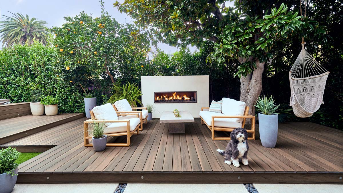 A backyard oasis decorated with orange trees and greenery built with dark brown Pecan decking from the Legacy Collection.