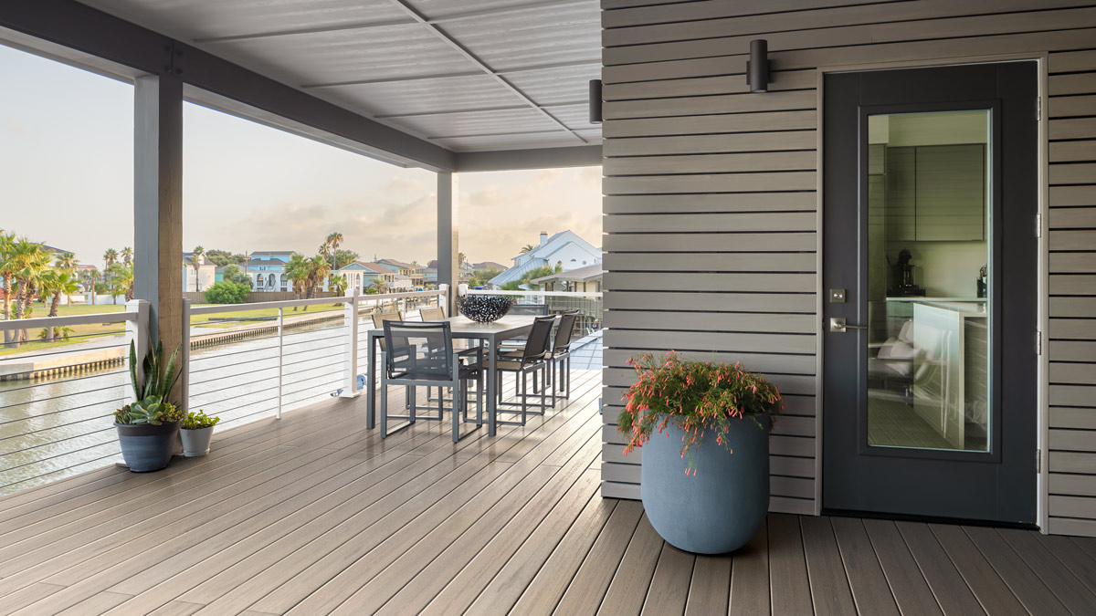 Stylish deck on a home near a canal featuring railing with a horizontal cable rail infill