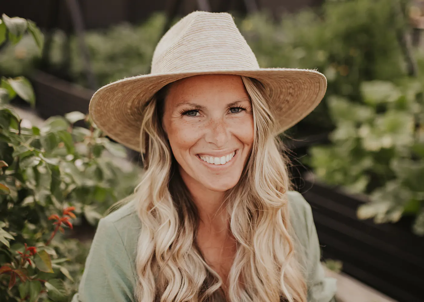 Headshot of Sarah Wagner against a background encompassing green leafy foliage. 